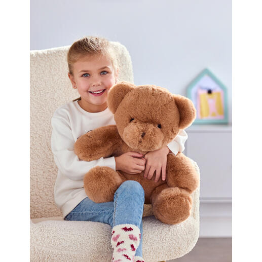 Fille avec un ours en peluche brun qui peut jouer un message vocal personnalisé.