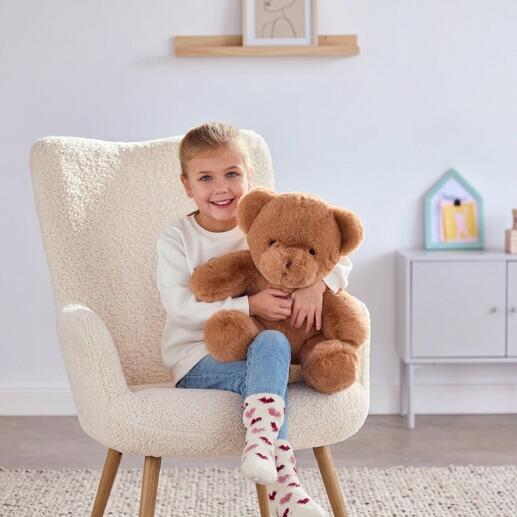 Fille avec un ours en peluche brun qui peut jouer un message vocal personnalisé.