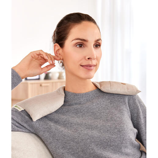 Femme portant un chauffe-épaule assise confortablement sur le canapé