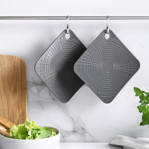 Deux gants de cuisine en silicone gris suspendus à une barre dans une cuisine moderne.