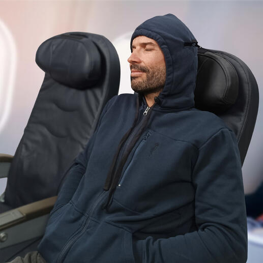 Homme en hoodie de voyage assis détendu dans un avion avec une capuche sur la tête.