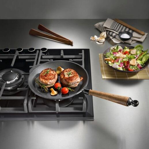 Poêle en fonte sur la cuisinière avec de la viande et des légumes frits
