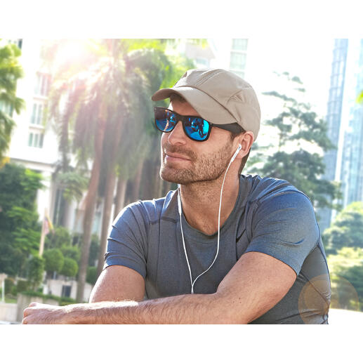 Homme avec casquette de refroidissement beige et lunettes de soleil assis à l'extérieur