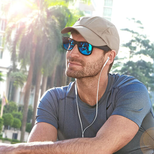 Homme avec casquette de refroidissement beige et lunettes de soleil assis à l'extérieur
