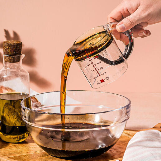 Personne versant de l'huile d'un verre mesureur dans un bol.