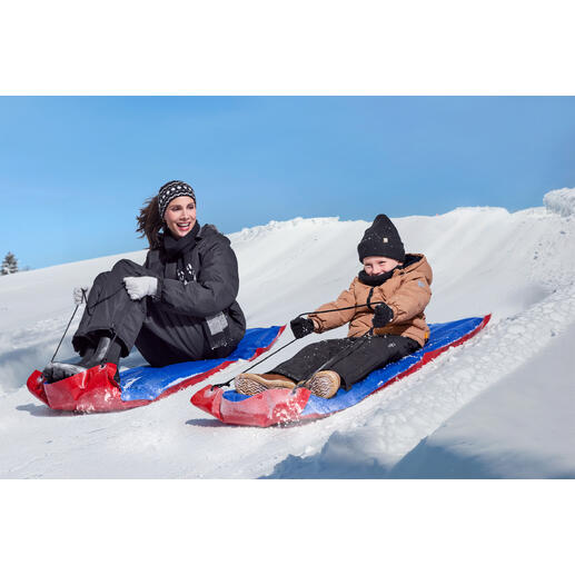 Femme et enfant glissant sur des traîneaux XL dans la neige.