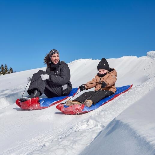Femme et enfant glissant sur des traîneaux XL dans la neige.