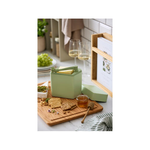 Boîte de fraîcheur pour fromage avec coupeur sur une planche en bois à côté de crackers et de miel.