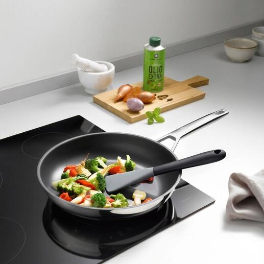 Spatule en silicone flexible dans une poêle avec des légumes mélangés.