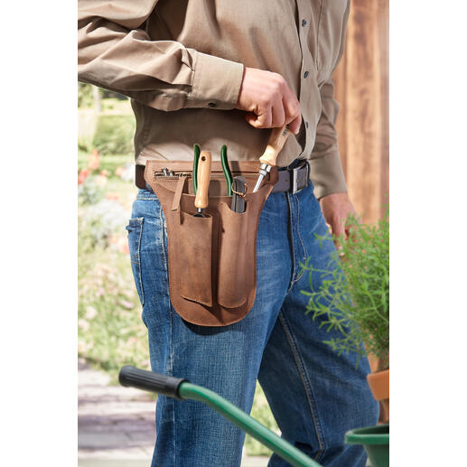 Homme portant une ceinture à outils en cuir de buffle, remplie d'outils de jardin.
