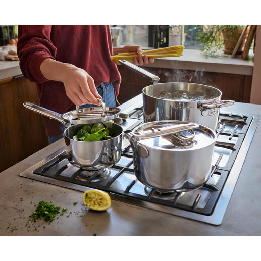 Set de casseroles avec poignée pliable, une casserole et deux casseroles avec des légumes sur la cuisinière.