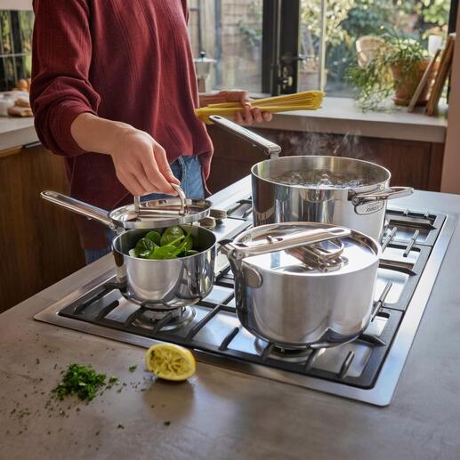 Set de casseroles avec poignée pliable, une casserole et deux casseroles avec des légumes sur la cuisinière.