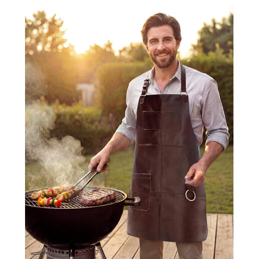 Homme barbecuant avec un tablier en cuir de buffle dans le jardin.