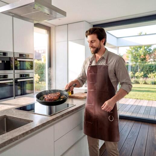 Homme portant un tablier en cuir de buffle cuisinant dans une cuisine moderne.
