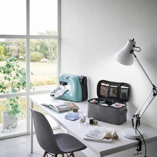 Petite boîte à outils gris clair avec plusieurs compartiments sur une table.