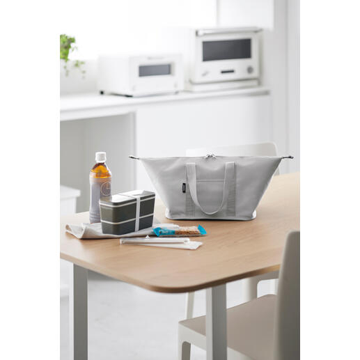 Sac isotherme Vario gris clair sur une table, entouré de collations et de boissons.