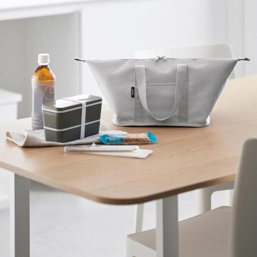 Sac isotherme Vario gris clair sur une table, entouré de collations et de boissons.