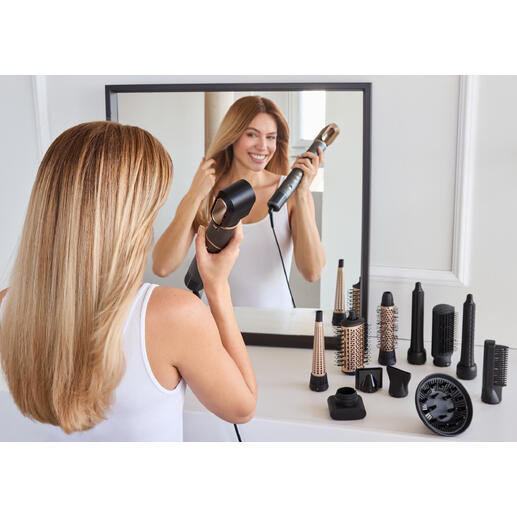 Femme coiffe ses cheveux avec un styliste 12-en-1 devant un miroir.