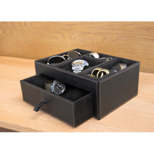 Boîte de rangement noire en cuir contenant divers accessoires comme des montres et des lunettes.