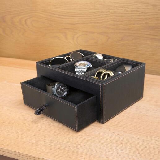Boîte de rangement noire en cuir contenant divers accessoires comme des montres et des lunettes.