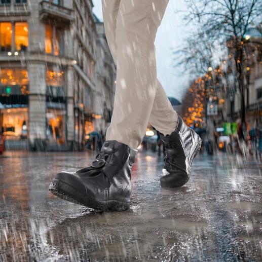 Personne portant des bottes noires avec des couvre-chaussures en silicone sous la pluie sur une rue mouillée.