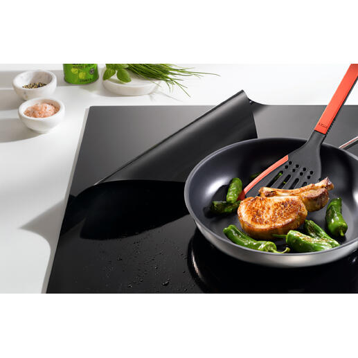 Poêle avec courgettes et un côtelettte sur une protection de plaque à induction