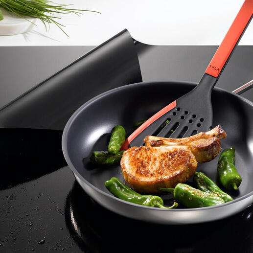 Poêle avec courgettes et un côtelettte sur une protection de plaque à induction
