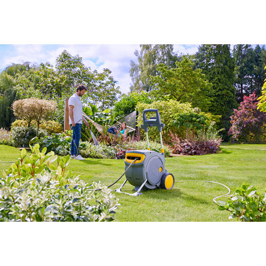 Homme arrosant avec un tuyau d'un enrouleur de tuyau fermé