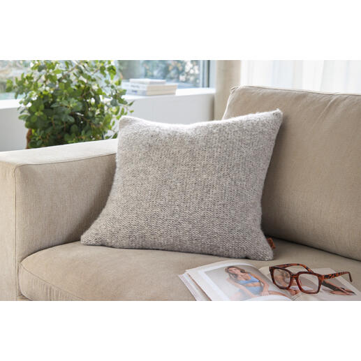 Coussin en alpaga-lin sur un canapé clair avec des lunettes et un magazine.