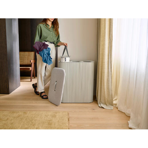 Femme avec des vêtements colorés debout à côté d'un collecteur de linge.