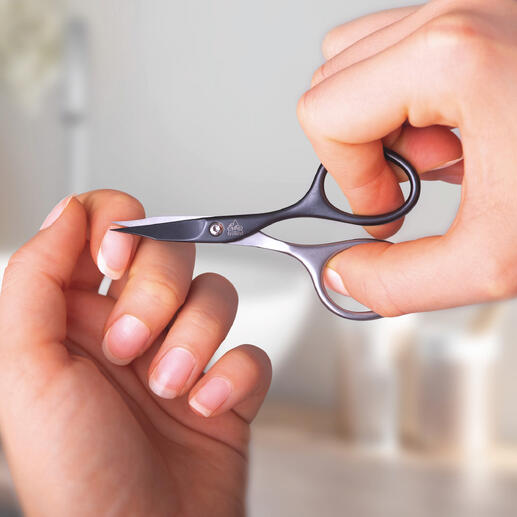 Personne utilisant des ciseaux de manucure auto-aiguisants pour couper son ongle.