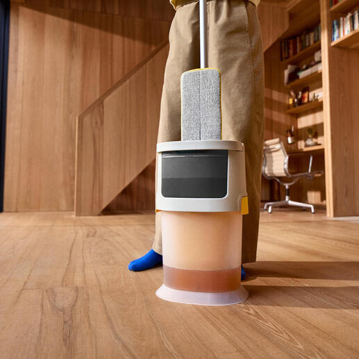 Robot de nettoyage avec seau sur un sol en bois.