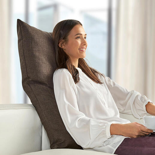 Femme avec coussin de dos marron sur un canapé blanc.