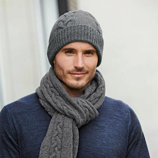 Homme portant un bonnet en tricot torsadé gris et une écharpe, vêtu d'un pull bleu.