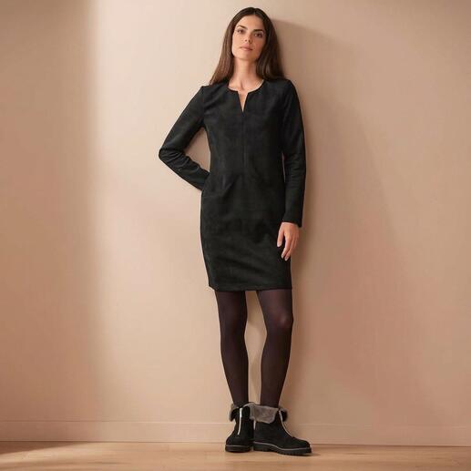 Femme en robe Alcantara® noire à manches longues, appuyée contre le mur.