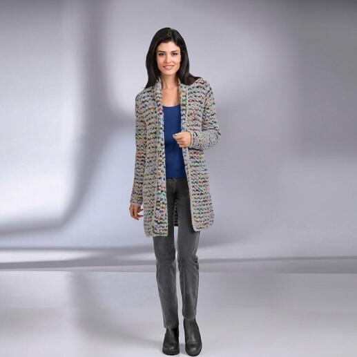 Femme dans un cardigan tricoté à main multicolore se tient souriante.