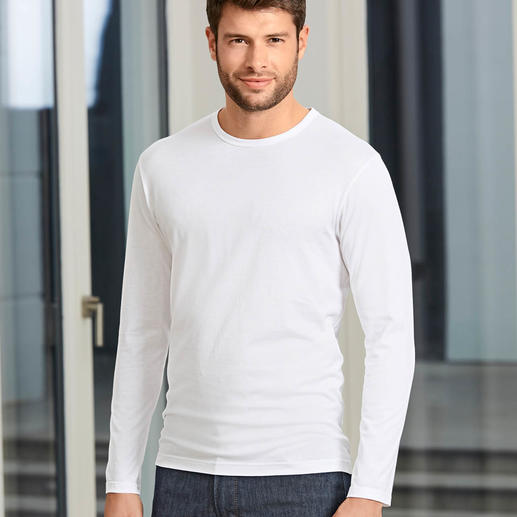 Homme en t-shirt Sunspel blanc, debout devant des fenêtres lumineuses.