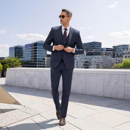 Homme en costume bleu avec des lunettes de soleil marche sur un toit avec vue sur la ville.