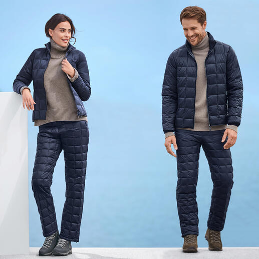 Homme et femme en veste et pantalon en duvet Taion, tous deux en bleu foncé, devant un fond bleu.