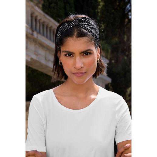 Femme portant un bandeau en soie Roeckl à pois, regardant l'objectif.