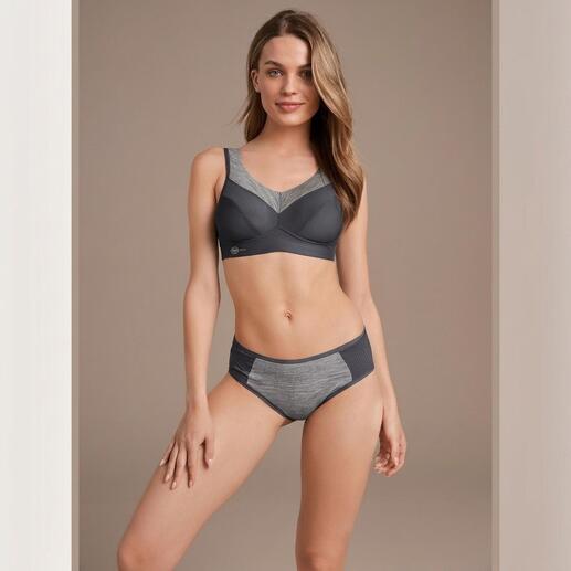 Femme portant un soutien-gorge de sport et une culotte de design sombre, souriante.