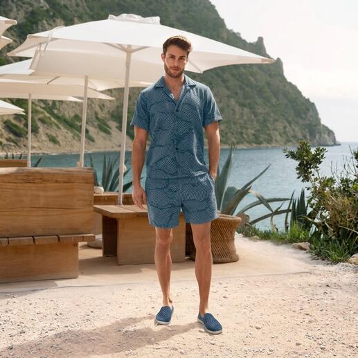 Homme en chemise en éponge rayée et shorts se tient sur la plage
