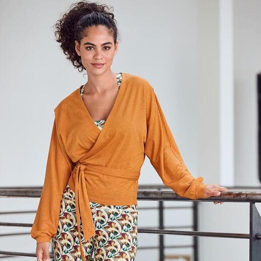 Femme en tenue Mandala avec un gilet croisé et des leggings, souriante.