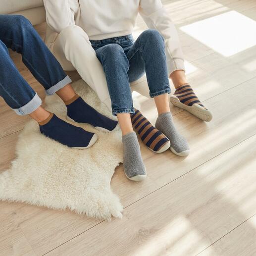 Chaussettes de maison en marine, gris et rayées sur un sol clair.