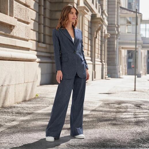 Femme en costume look denim avec une coupe ample, se tient dans un environnement urbain.