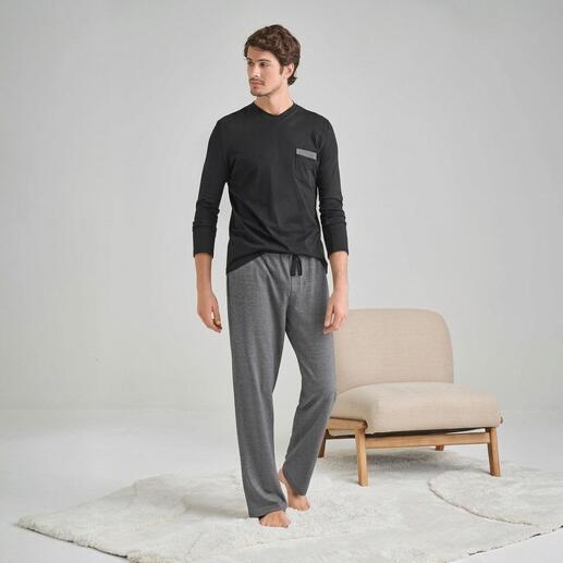 Homme en t-shirt noir à manches longues et pantalon de pyjama gris debout sur un tapis.