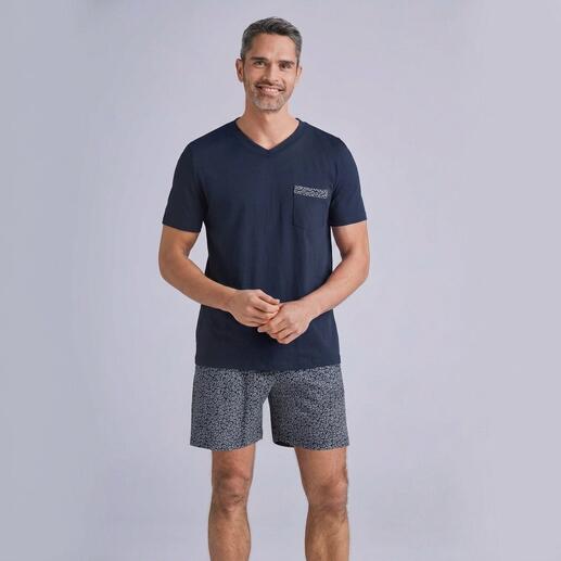 Homme en T-shirt bleu marine et shorts gris, souriant devant un fond neutre.