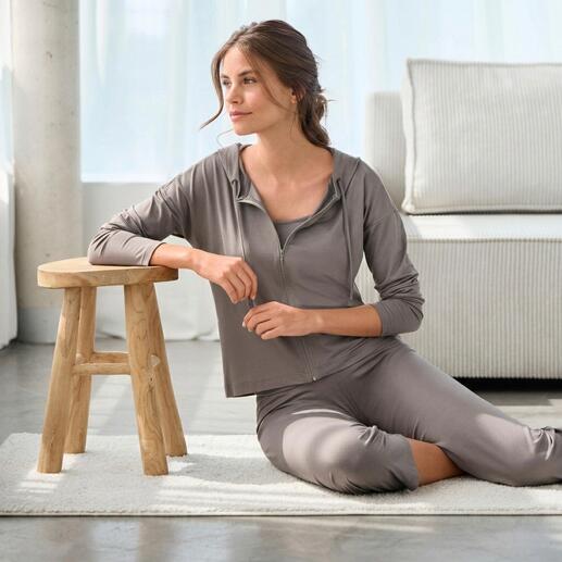 Femme assise dans une combinaison loungewear élégante sur un tapis.