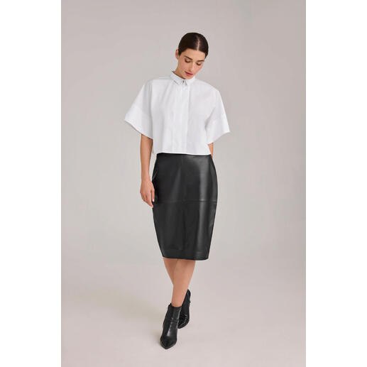 Chemise oversize Boxy blanche, portée par une femme avec une jupe noire.