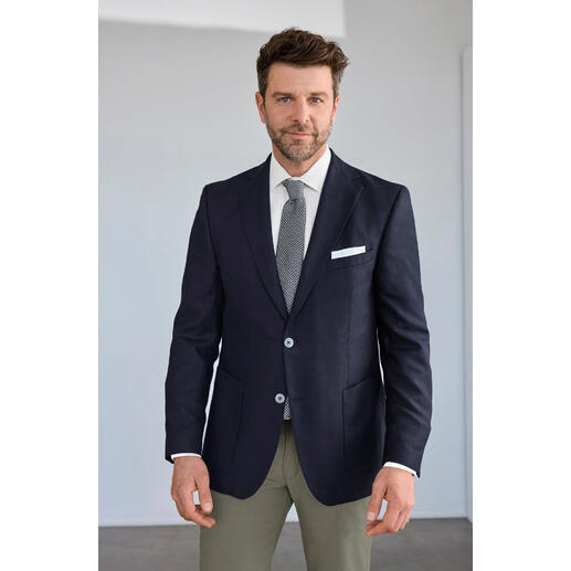 Veste en soie Carl Gross Homme en veste en soie Carl Gross avec cravate, posé devant un fond neutre.
